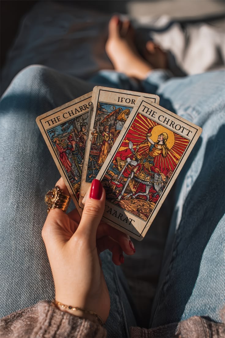 Trois cartes de tarot tenues en main